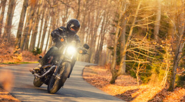 Hombre joven manejando moto en la carretera por el bosque