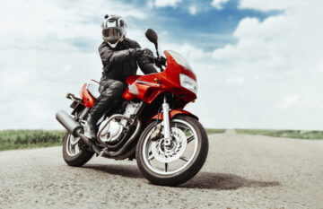 Hombre conduciendo su moto en la carretera mientras tiene goza de una cobertura de una aseguradora de moto