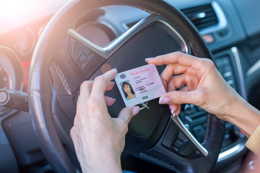 Mujer sosteniendo entre sus dedos su nueva licencia para conducir