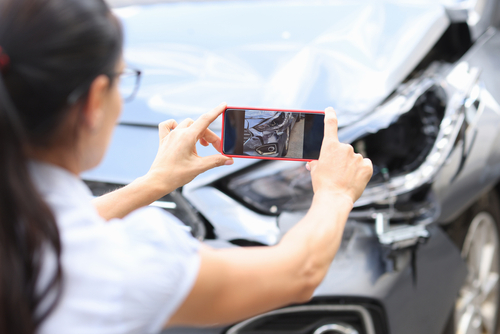 Mujer tomando fotografía para saber cómo reportar un accidente de carro 