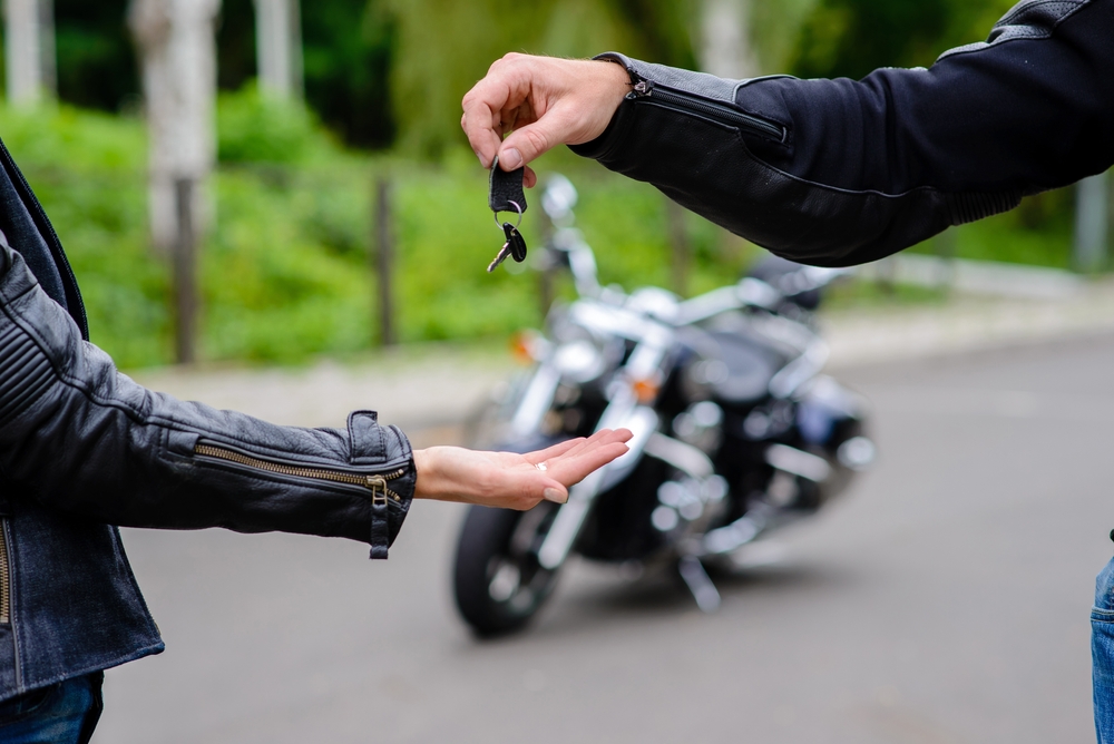 Hombre entregando llaves tras contrato de compraventa de motocicleta