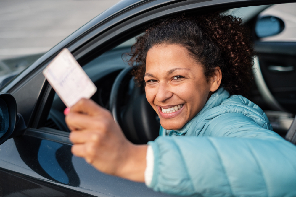 woman holding her reinstated drivers license smiling inside a car thanks to sr22 insurance