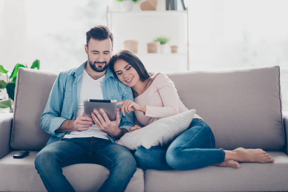 couple in living room looking for cheap car insurance on tablet
