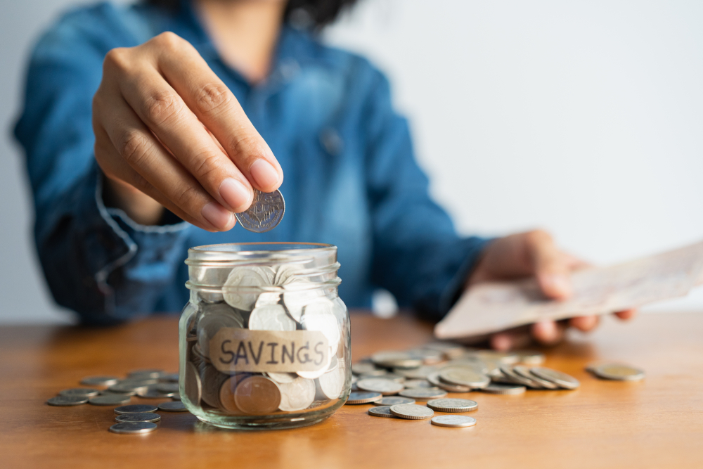 woman putting coins in jar that says savings