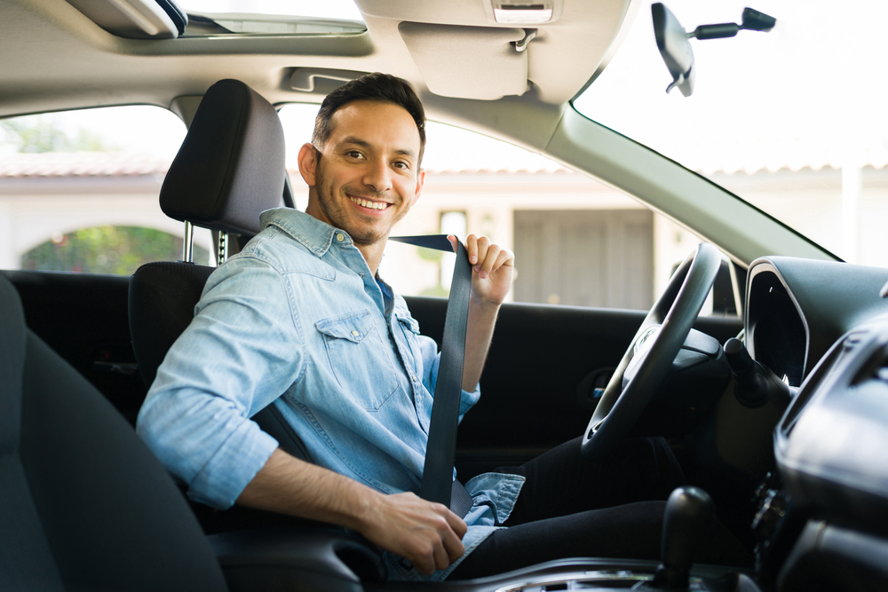 smiling young man putting seat belt on car with driving record on texas