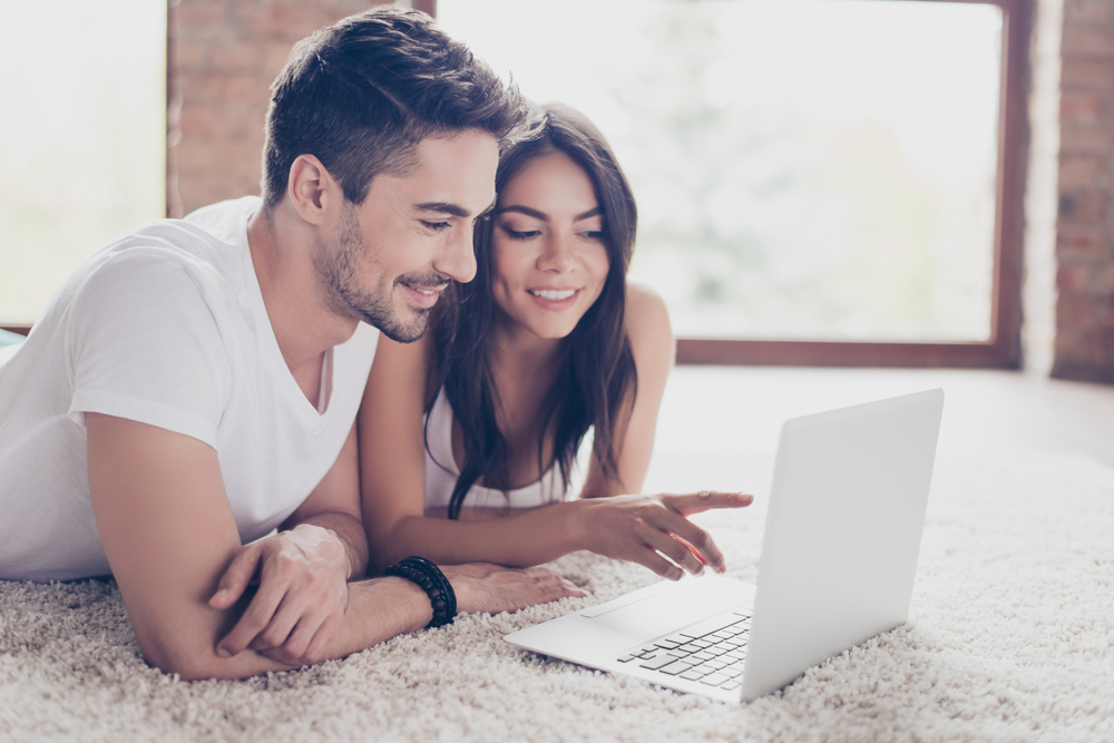 happy couple reading auto insurance policy in laptop to understand it
