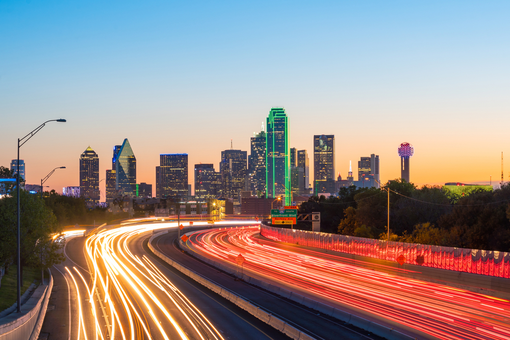 dallas skyline at twilight with highway filled with cars with texas car insurance