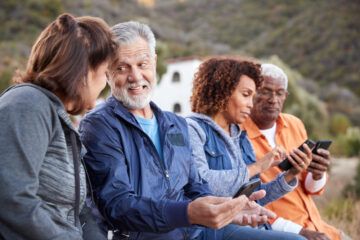 four senior citizens looking at smartphones together