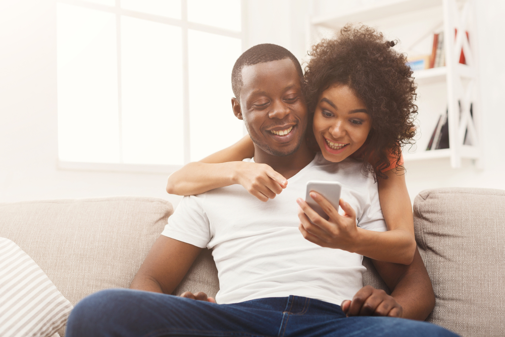 african american couple looking at cars online in phone