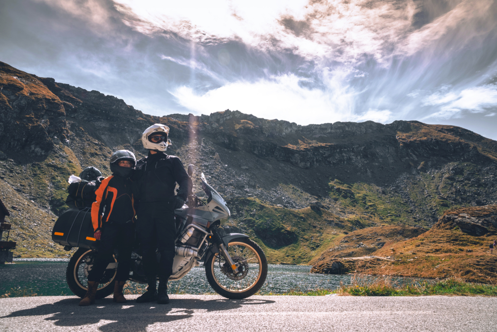 couple in front of motorcycle with a scenic mountain in the background