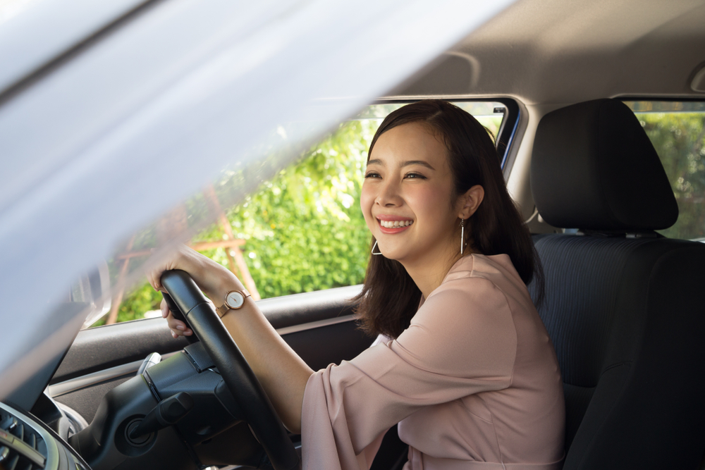 smiling asian young woman driving a car in texas with a teen license