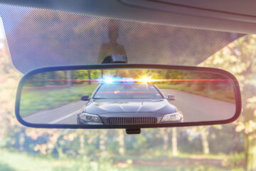 rear view mirror in car with the reflection of a cop car