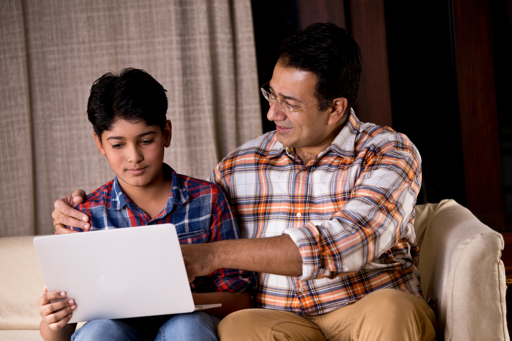 father and teen son looking at laptop to file a teen drivers license in texas