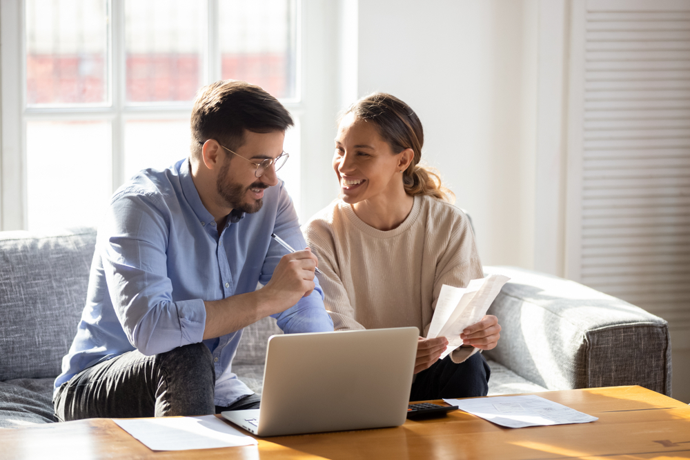 young couple in living room looking for renters insurance in dallas in laptop