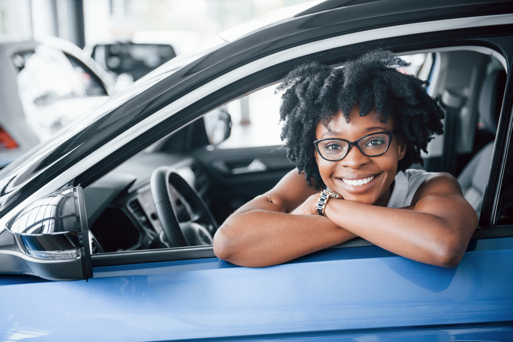 oung african american woman sits inside of new modern car.