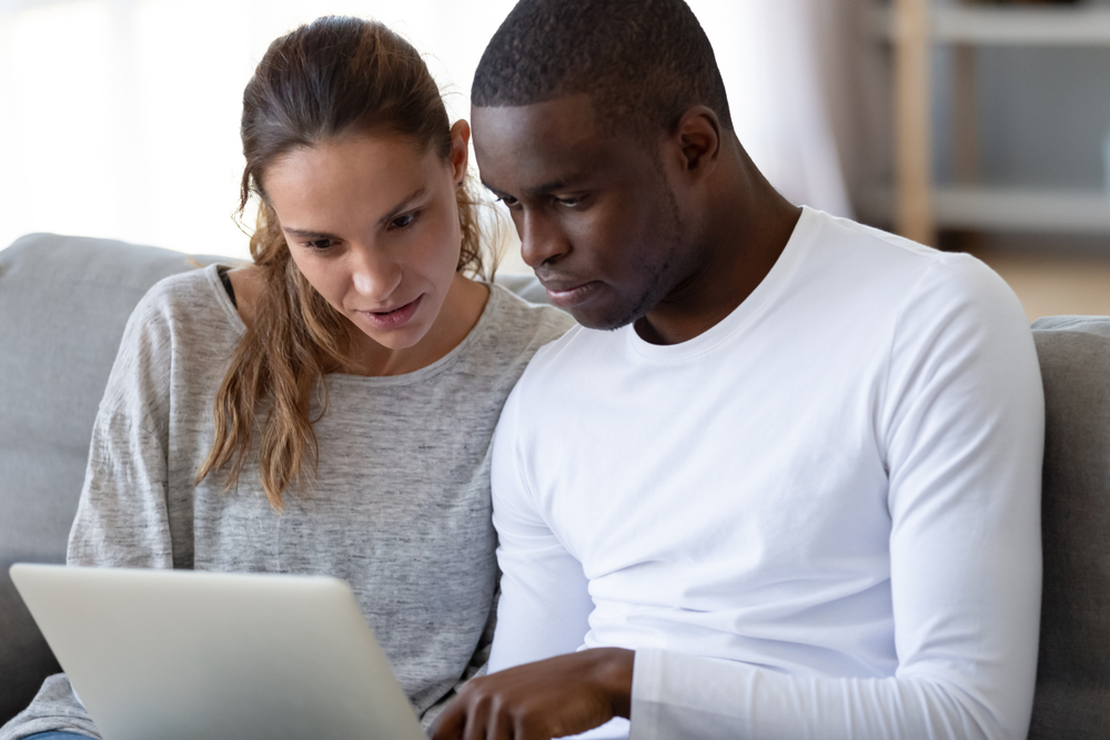 serious couple lookig at renters insurance options at laptop