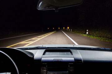 steering wheel of car driving at night on highway