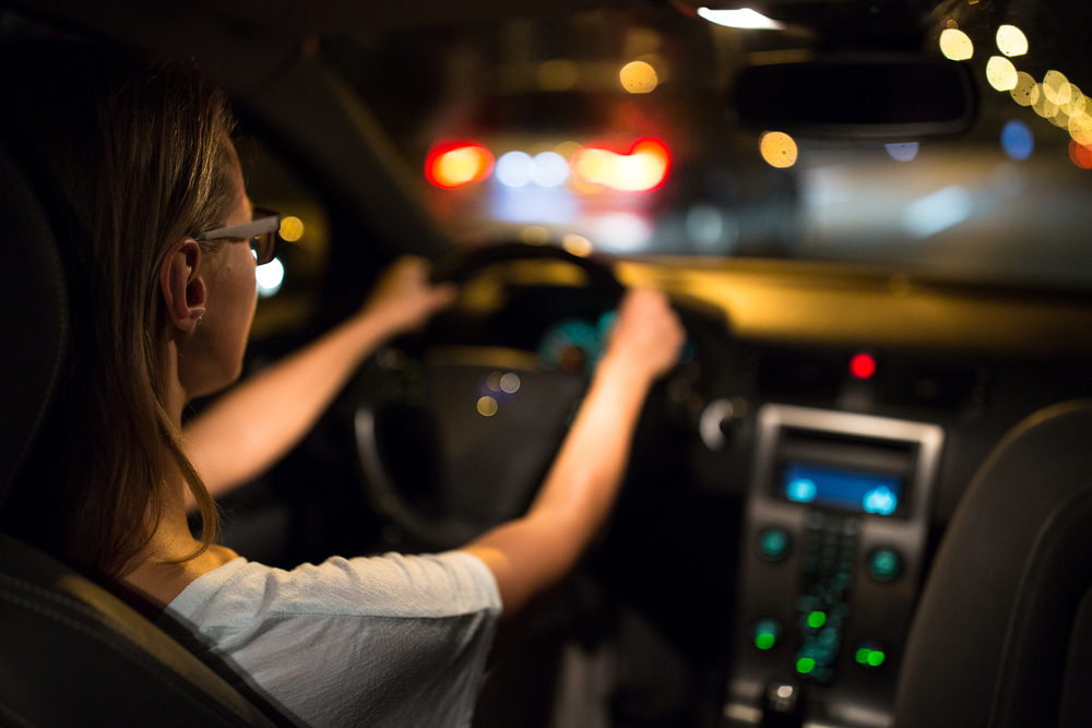 caucasian woman with two hands on wheel driving at night