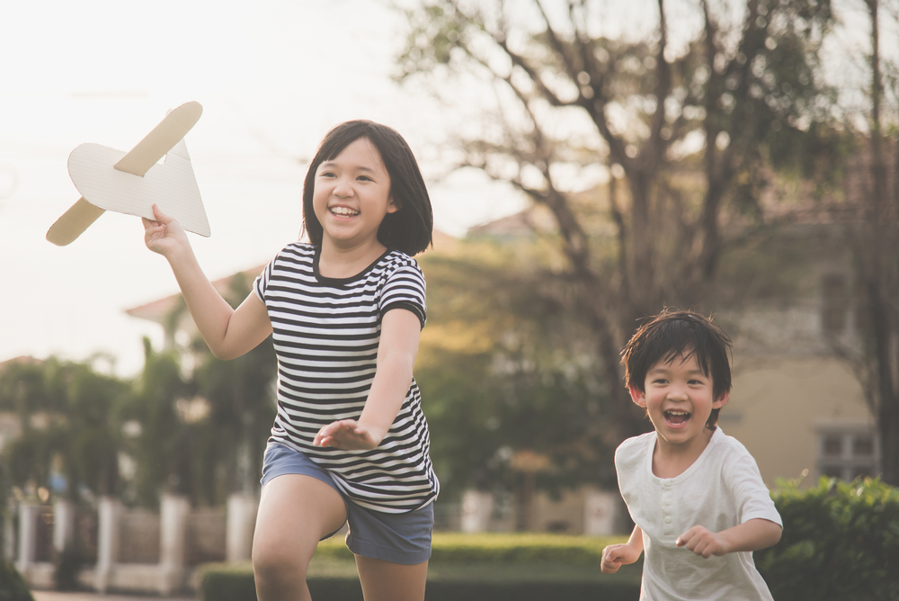young asian children running outside and laughing