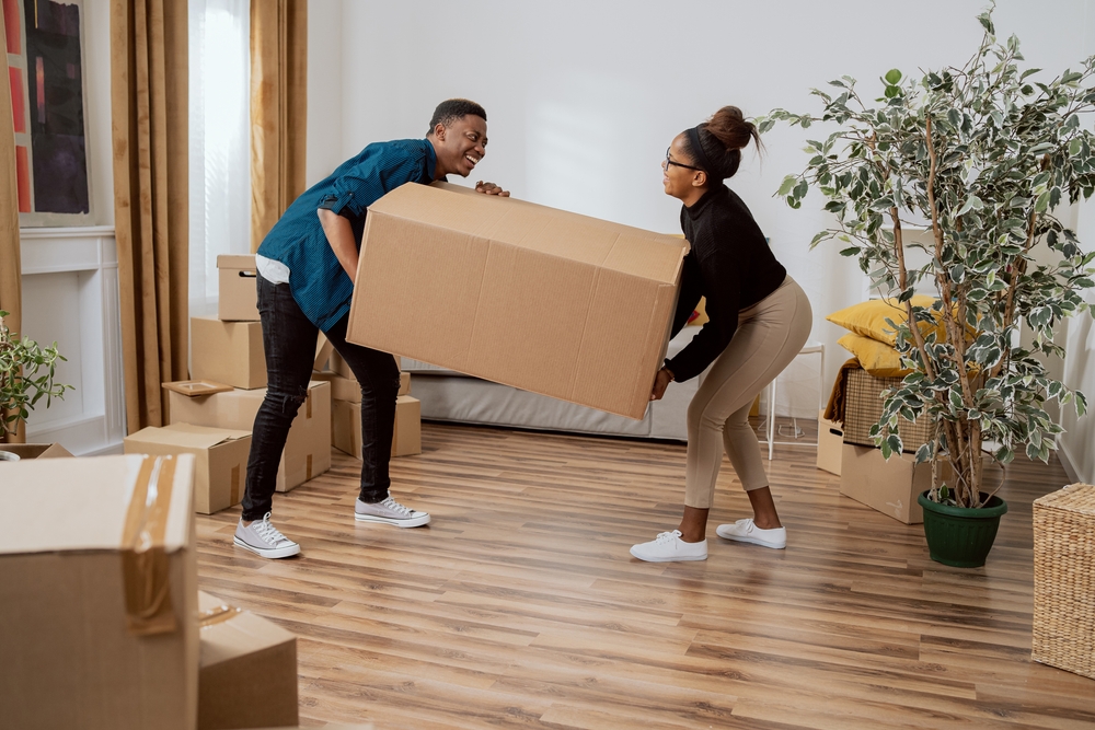 young couple moving boxes into apartment