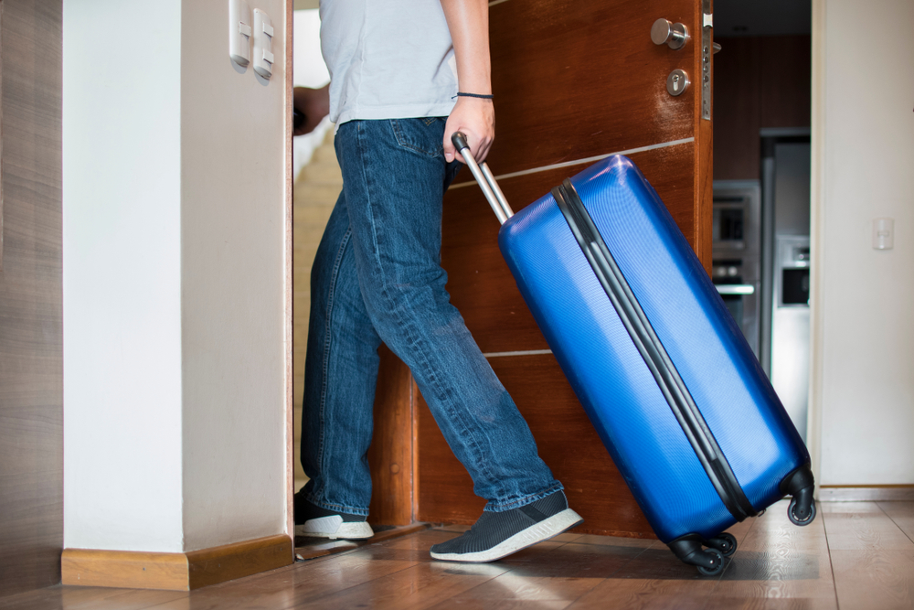 man leaving apartment with suitcase