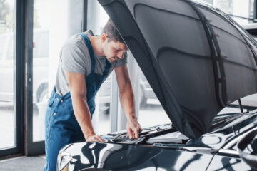 man with hood up inspecting vehicle