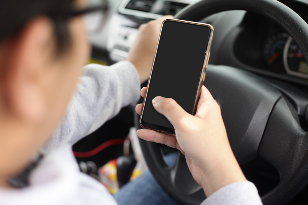 Man looks at phone in distracted driving while behind the wheel