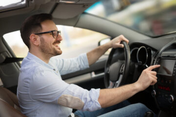 man driving car adjusting radio