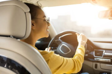 young african american woman behind wheel of car smiling