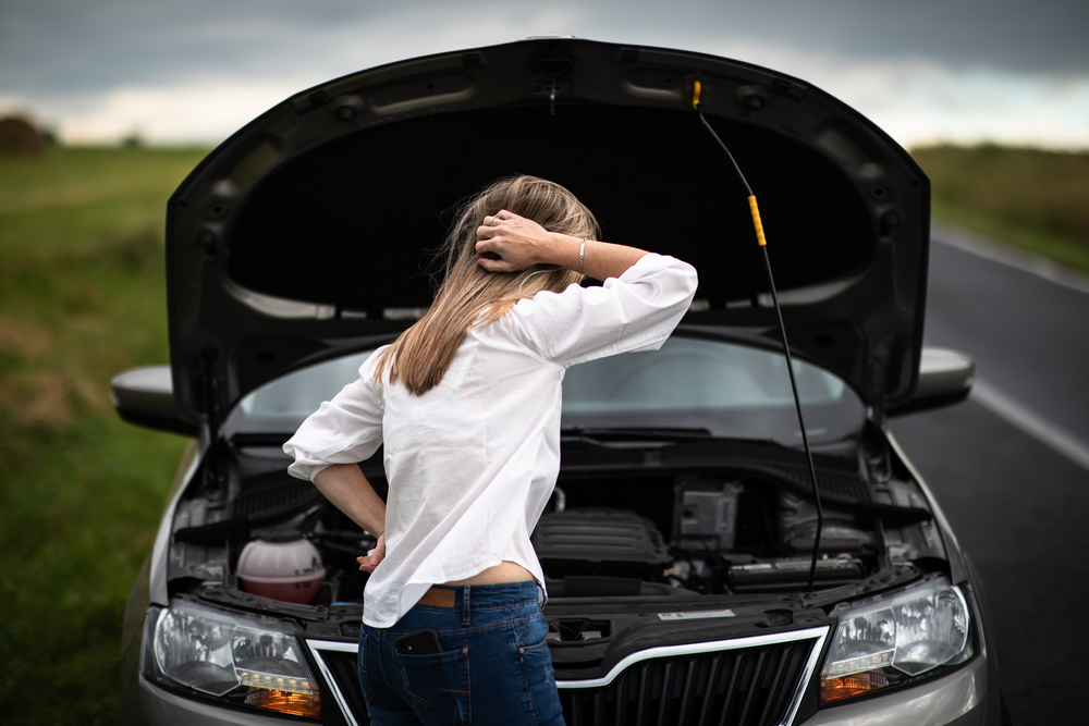 woman standing in front of broken down car