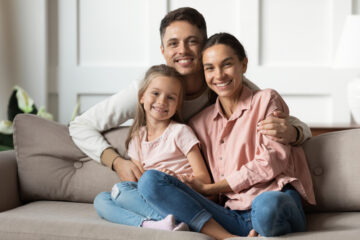 family of three smiling on the couch