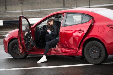 Young woman is upset after a car accident in a red car